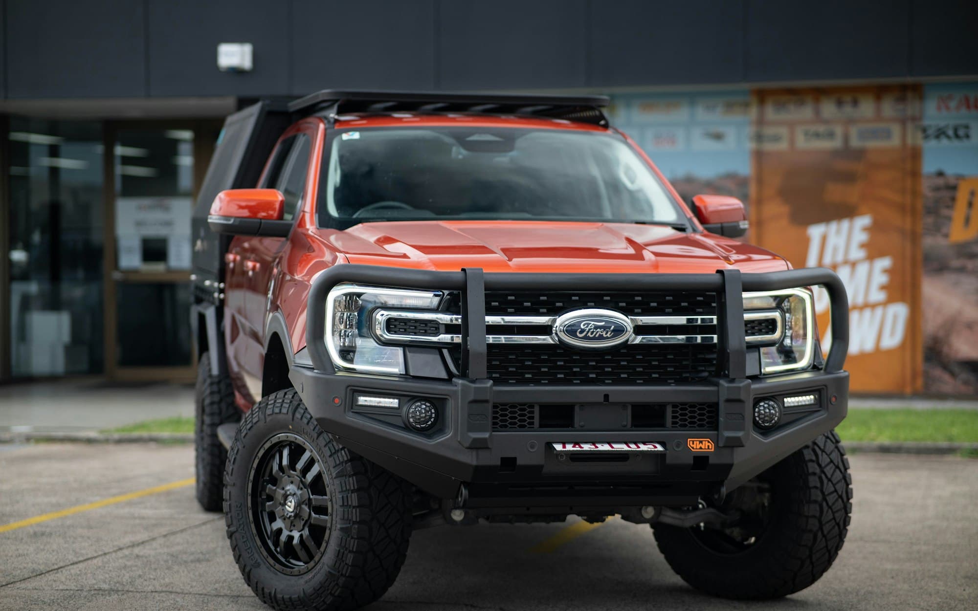 An orange next-generation Ford Ranger fitted with a bull bar and canopy