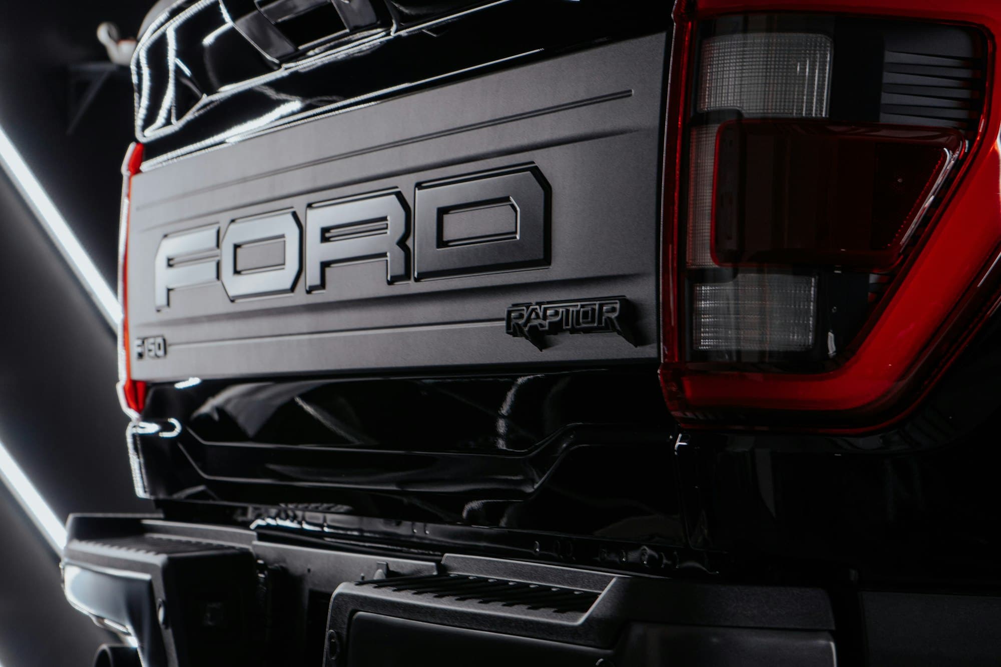 The tailgate of a black third-generation Ford F-150 Raptor in a studio