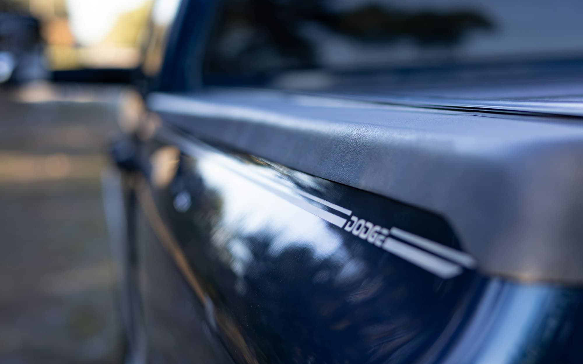 Close-up of a soft tonneau cover clamped to the bed rail of a blue Dodge pickup